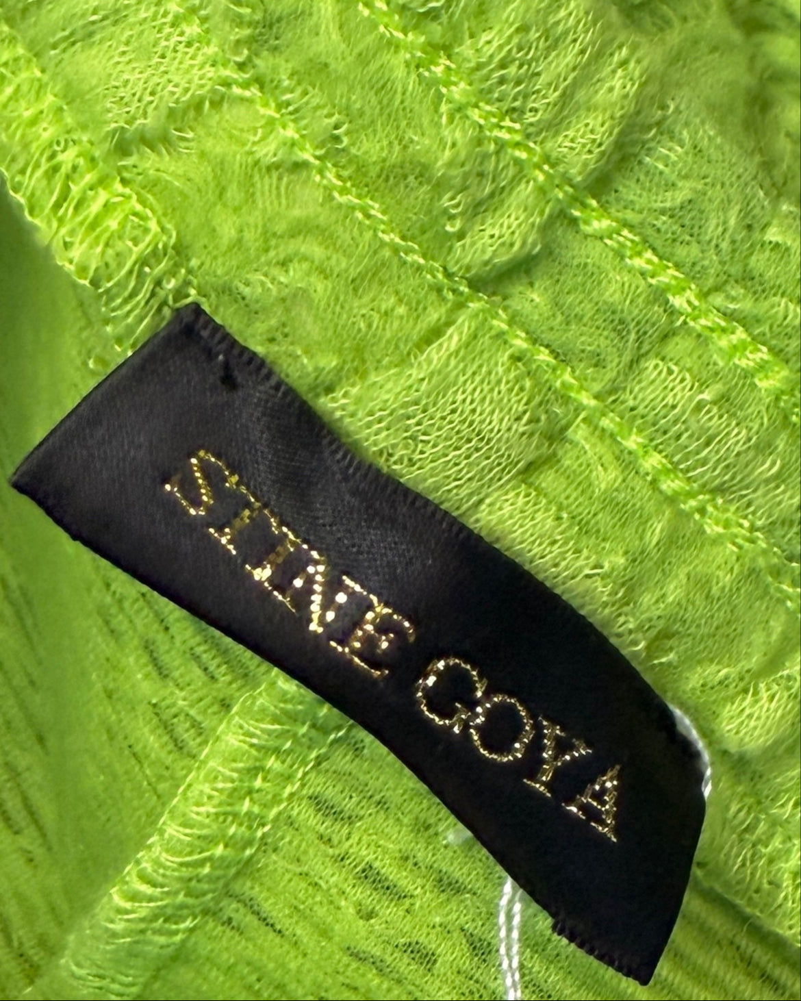 Close-up of a lime green fabric with a 'Stine's Goya' label.